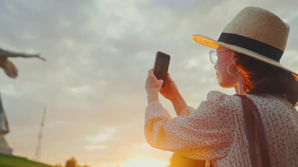 A young tourist in a hat taking a photo of the Motherland on the Mamayev Kurgan alt