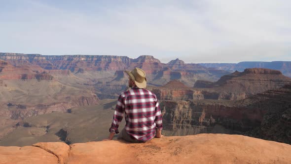 A Hiker Man Sits, Watching A Breathtaking View Of Grand Canyon Alone alt