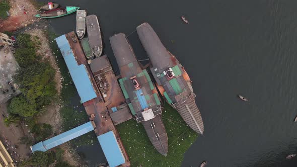 Wheel steamers at the pier in the Buriganga river bank with boats - aerial descending shot alt