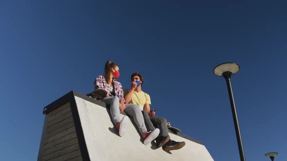 Happy caucasian woman and man friend wearing face mask, sitting and laughing alt