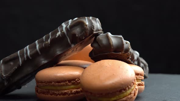 Chocolate and Macaroon Rotate on a Black Background and the Hand Takes Candy Sweets are Spinning alt