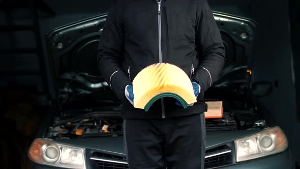 Car mechanic in car service bends in the hands of the car air filter alt