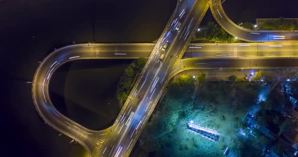 Top down night hyperlapse of freeway ramps and loops with heavy traffic with light streaks. Camera s alt