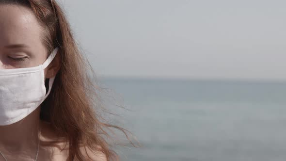 Half Face Portrait of a Young Woman Wearing Protective Mask on Public Beach alt