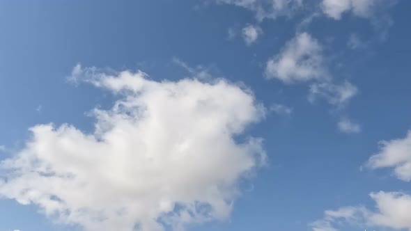 White Clouds Flying On Blue Sky With Sun Rays alt