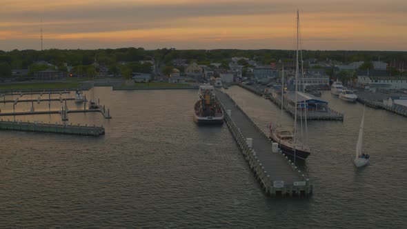 Aerial Pan of a Neighborhood by the Water and Docked Boats at a Marina at Sunset alt