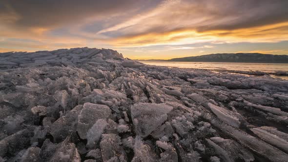 Sunset timelapse moving over broken ice on lake alt