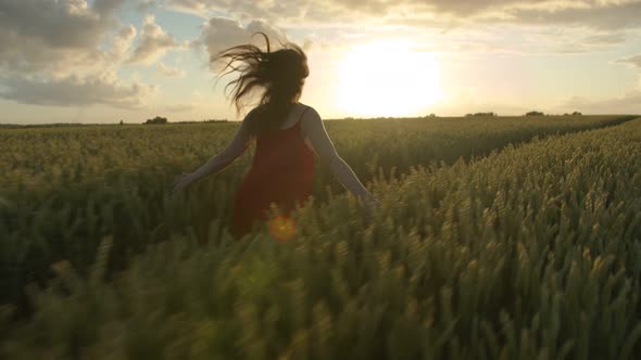 Beautiful Woman in a Red Dress Runs Against the Sunset