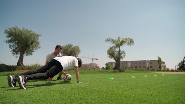 A Young Guy with a Personal Fitness Trainer Performs Pushups and Resistance Runs for Endurance and