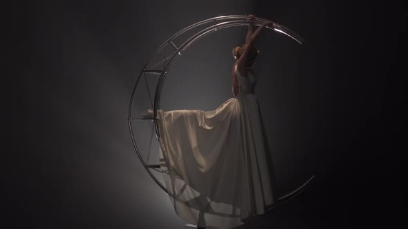 Graceful Acrobat Performs Movements on a Metal Structure Moon in the Form of a Month. Smoke alt