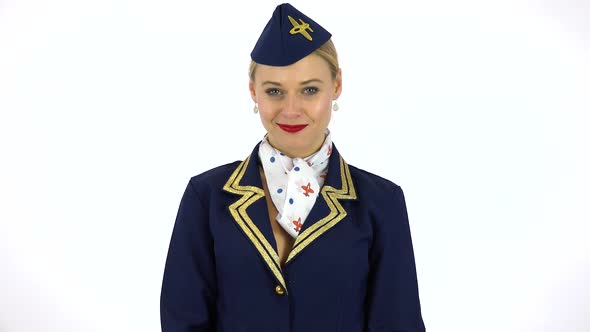 A Young Beautiful Stewardess Nods and Smiles at the Camera - White Screen Studio alt