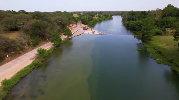 Aerial footage of the Blanco River i Blanco Texas. Drone approaches a dam with people swimming alt