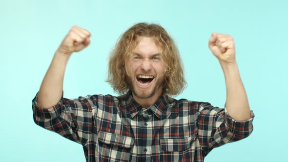 Slow Motion of Cheerful Blond Guy with Beard Raising Hands Up and Rooting for Sport Team Smiling