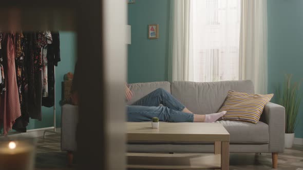 Young girl is lying on couch and anxiously talking on phone