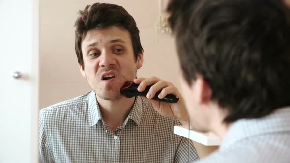 Machine Shave Facial Hair. Young Handsome Man Dry Shaving with Electric Trimmer