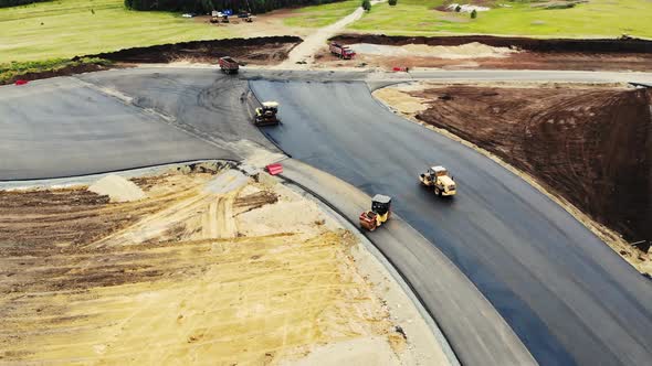 Aerial View of the Yellow Road Rollers That Lay the Asphalt of the Test Ground for Cars alt