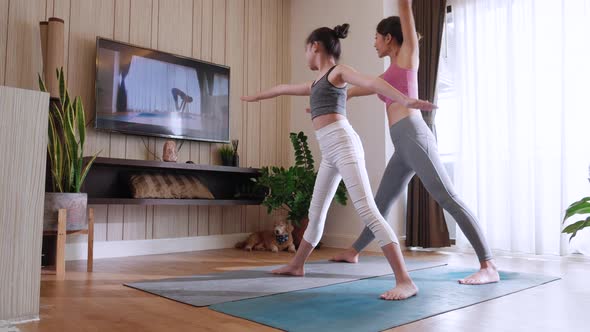 Back view, Mom and girl practicing yoga together by watching live video tutorial TV online at home