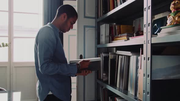 Man holding a book standing in front of a shelf in the office alt