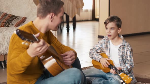 Happy father and son playing guitars and singing a song