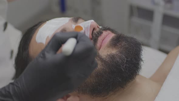 Closeup of a Young Man's Face with a Cleansing White Mask on His Face alt