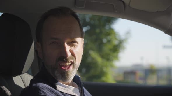 A Middleaged Handsome Caucasian Man Makes Faces at the Camera in a Car  Closeup