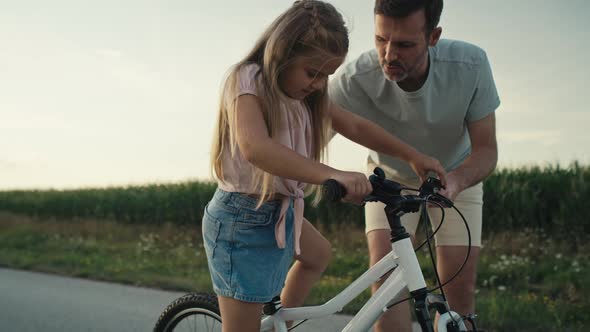 Caucasian Father teaching his little daughter how to ride a bike. Shot with RED helium camera in 8K. alt