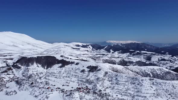 Aerial drone of an amazing panoramic view of a mountain range covered with snow during a sunny day