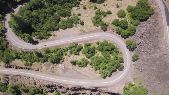 Aerial top down static view of motorcycle riding on a spectacular scenic horseshoe hairpin bend road alt