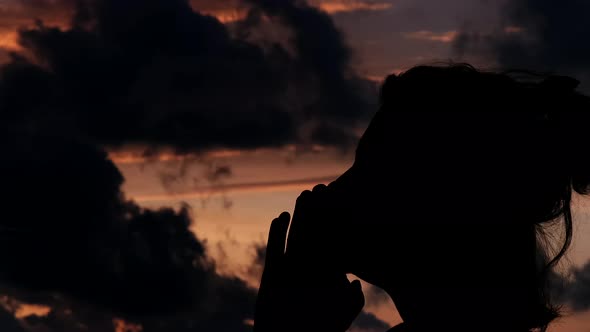 silhouette of woman meditating at gorgeous cloudy sunset , silhouette of woman praying