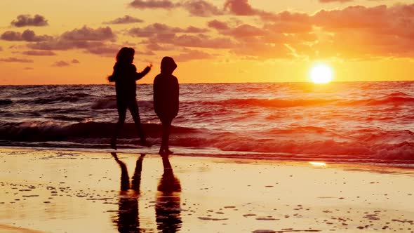 Two Young Girls Watching Sunset on Beach.