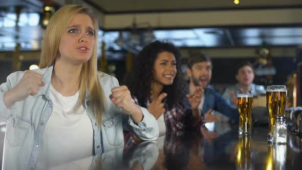 Beautiful Blonde With Friends Watching Sports in Pub, Upset About Losing Game alt
