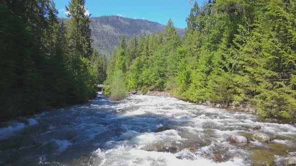 Aerial Drone Traveling Along Water Rapids With Mountains And Evergreen Forest 4