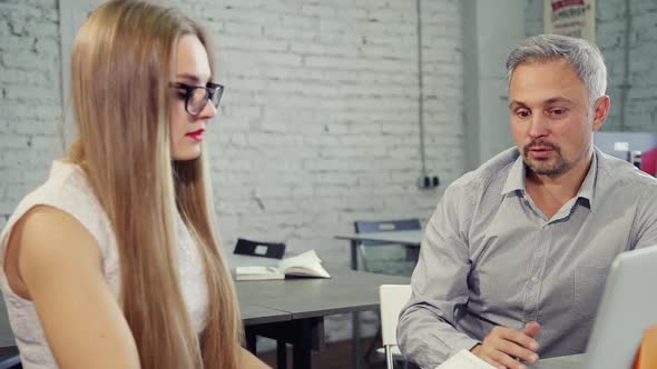 Successful Businessman Discussing Startup with Female Colleague at Table in Office Interior.