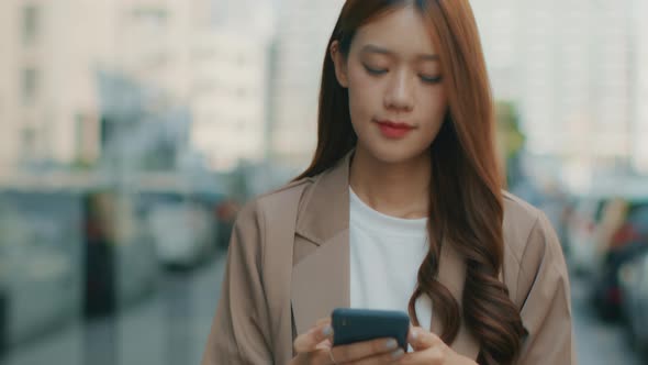 Asian Businesswoman using a mobile phone. Successful Asian Businessperson walking in the street