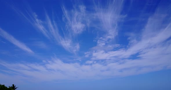 Wide angle birds eye travel shot of a white paradise beach and blue sea background in 4K alt