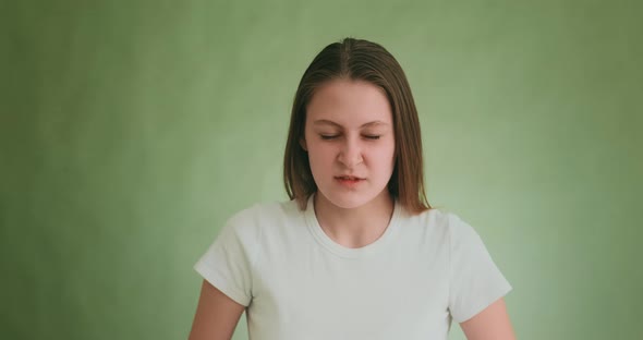 Aggressive Woman Clutches Head Posing for Camera on Green alt