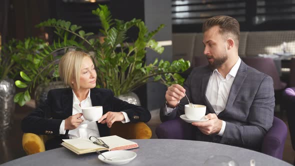 Handsome Businessman and Elegant Businesswoman Having Pleasant Conversation for a Cup of Coffee