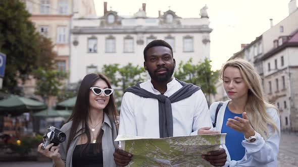 Cheerful Likable Mixed races Friends Walking on the City Street and Looking at Map alt