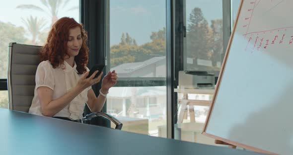 Medium shot of a young business woman ending a phone call while sitting in her office. Slow motion alt