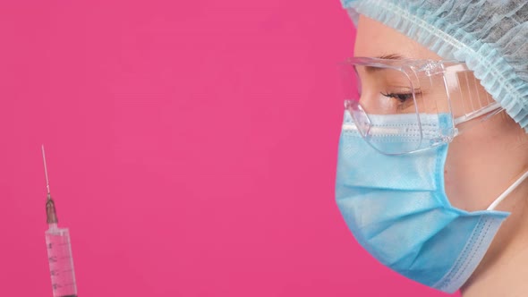 Serious Doctor in a Blue Medical Coat Safety Glasses and Medical Cap Looking Forward alt