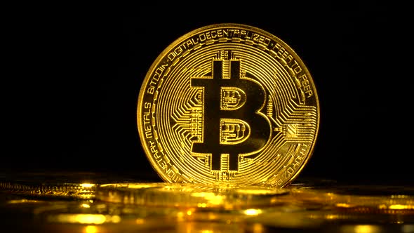 Scattered Bitcoins on the Surface Revolve on a Black Background. Close Up alt