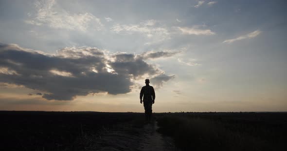 A Soldier Walks Across a Field at Sunset and Looks Around Silhouette alt