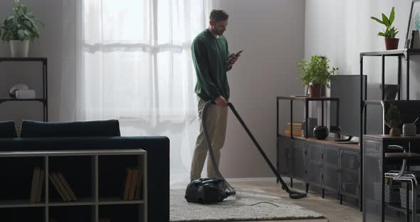Adult Man Is Doing Cleanup at Home and Browsing Social Networking in Smartphone Internet Addiction alt