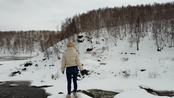 A Girl Stands on a Mountainside Overlooking the Winter Forest Mountains