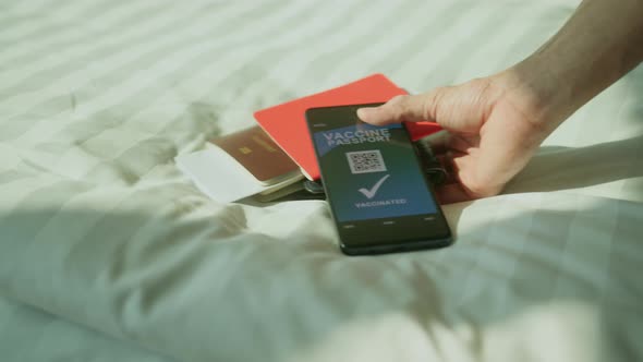 closeup asian traveller hand pick up passport and smartphone with vaccine passport alt