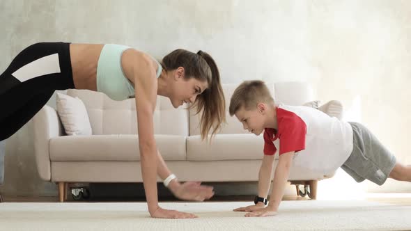 Family Training of Mom and Son Making Plank Exercise at Home Giving Five.