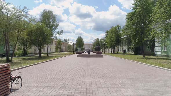 Girls with a stroller walks along a beautiful alley in a provincial city. 08 alt