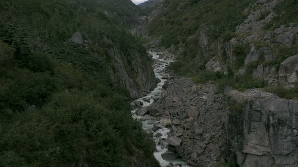 A small river flows within a rocky ravine. A sliding shot from Skagway, Alaska. alt