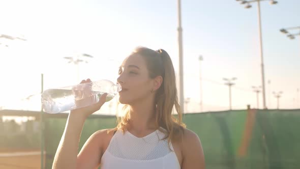 A Beautiful Woman Drinks Water After a Workout