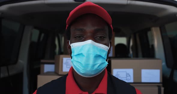 African man courier delivering packages with truck while wearing protective face mask alt